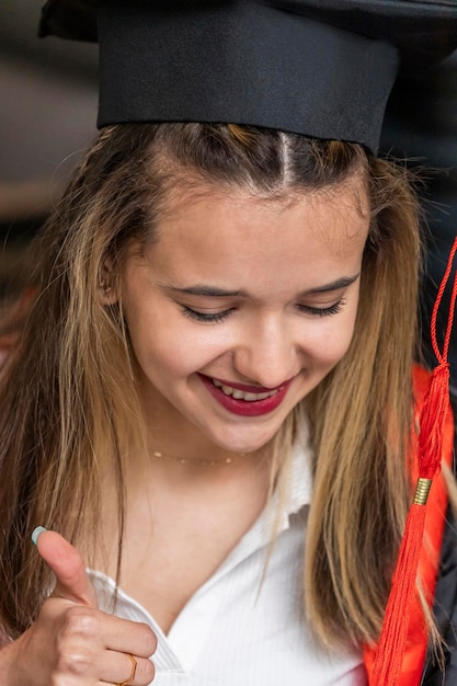 Close-up foto van een jonge student met afstudeerpet en gebaar duim omhoog