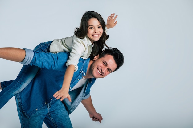 Close-up foto van een jonge vader en zijn kleine kind, die teder knuffelen en glimlachen, terwijl ze samen in de camera kijken.
