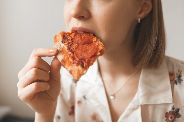 Close-up foto van een meisje bijt een stukje smakelijke pizza.