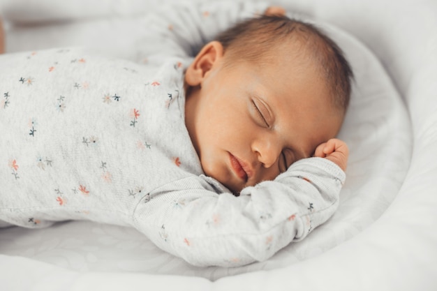 Close-up foto van een slapende baby in warme kleding met zwart haar die zich veilig voelt in zijn eigen bed