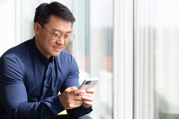 Close-up foto van een succesvolle Aziatische zakenman met behulp van de telefoon een programmeur in een shirt en bril