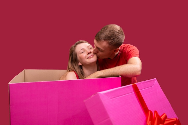 Foto close-up foto van een verliefde paar vriendin zittend in de grote huidige doos van roze kleur met c...