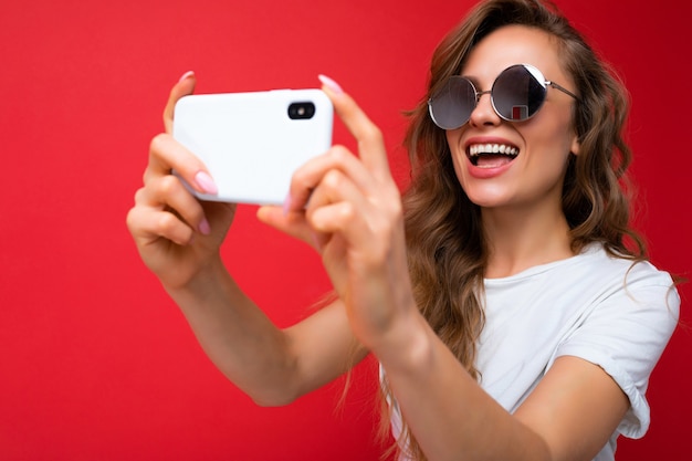 Close-up foto van gelukkige jonge blonde vrouw met mobiele telefoon die selfie foto maakt met smartphone