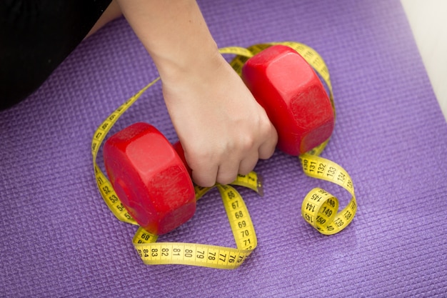 Close-up foto van hand tillen dumbbell bedekt met meetlint