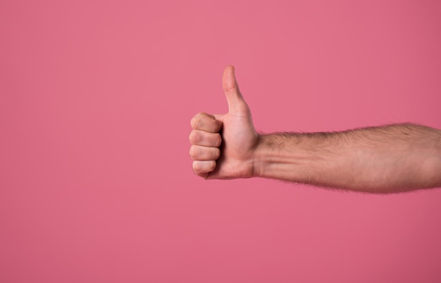 Close-up foto van mannenhand terwijl duim op roze achtergrond verschijnt