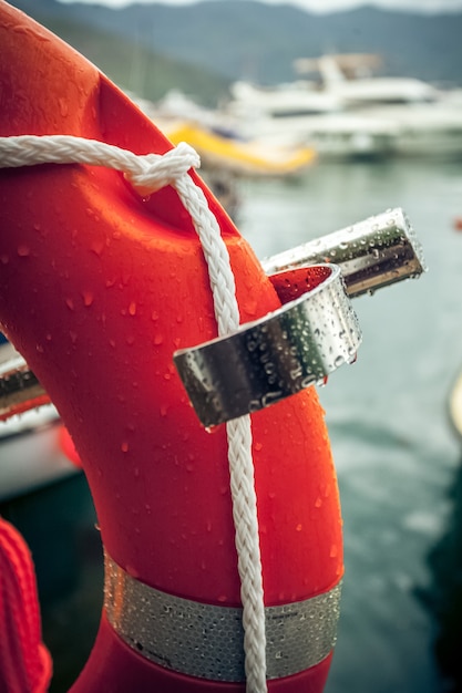 Close-up foto van rode reddingsboei met touw tegen zeehaven