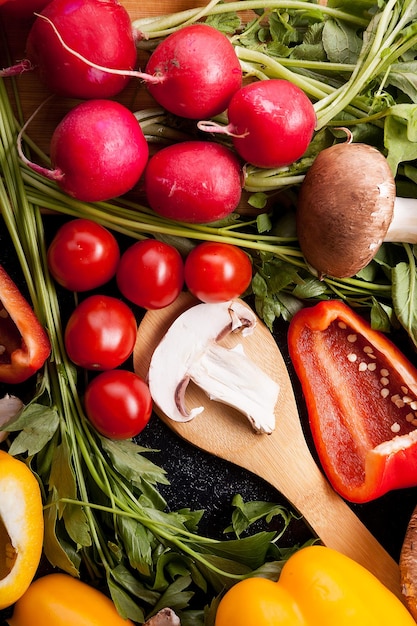 Close-up foto van verschillende soorten groenten op donkere achtergrond. Radijs, gesneden plakjes gele en rode paprika, champignons en groentewinkel