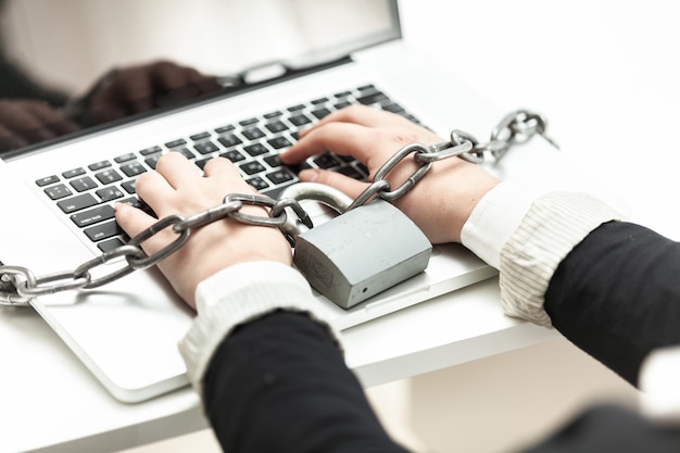 Close-up foto van vrouw opgesloten in ketting typen op laptop