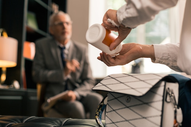 Close-up foto van vrouwelijke patiënten handen pillen nemen uit een pillendoosje in het kantoor van psychotherapeuten