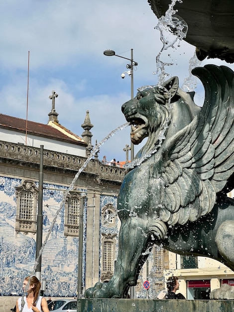 Close up of fountain of Lions 19th century fountain in Parada Leitao Square in historic city of Porto in Portugal The beautiful Carmo church on blurred background