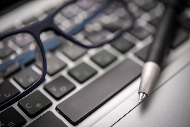 Close-up fountain pen on the keyboard with glasses