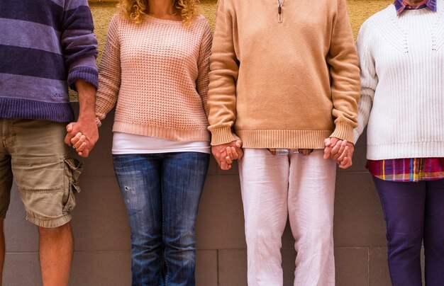 Primo piano di quattro persone che si tengono per mano insieme in strada con affetto e amore