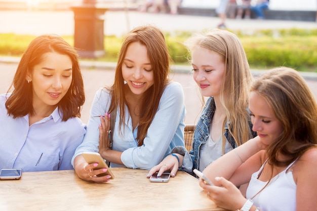 屋外でスマートフォンを使用している4人の女性のクローズアップ