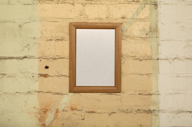 Photo close up of a framed blank picture hanging on a yellow brick wall