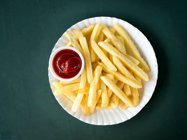 Close up French fries potatoes with ketchup on white dish.