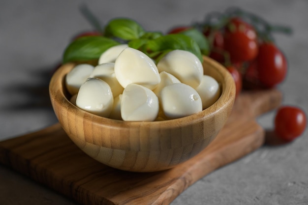 Близкий взгляд на свежий Apulian mozzarella сыр в деревянной чаше с свежим листом базилика