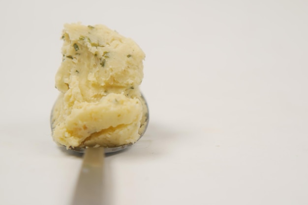 Close up of fresh butter on a spoon on white background