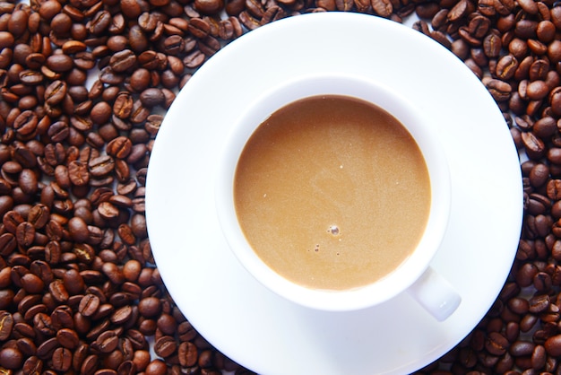 Close up of fresh coffee beans and coffee on table .