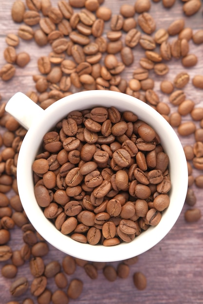 Close up of fresh coffee beans in a cup on black surface with copy space