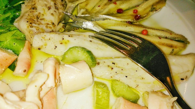 Photo close-up of fresh cooked fish with fork in plate