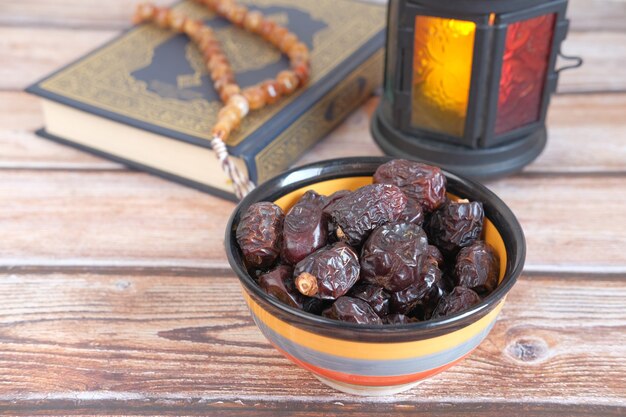 Close up of fresh date fruit in a bowl and quran on desk