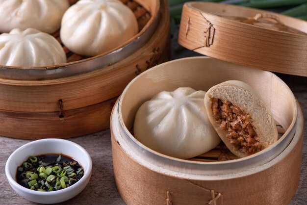 Close up of fresh delicious baozi Chinese steamed meat bun is ready to eat on serving plate and steamer close up copy space product design concept