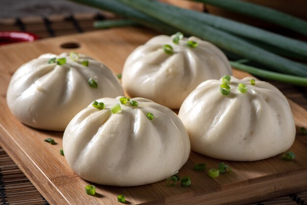 Photo close up of fresh delicious baozi, chinese steamed meat bun is ready to eat on serving plate and steamer, close up, copy space product design concept.