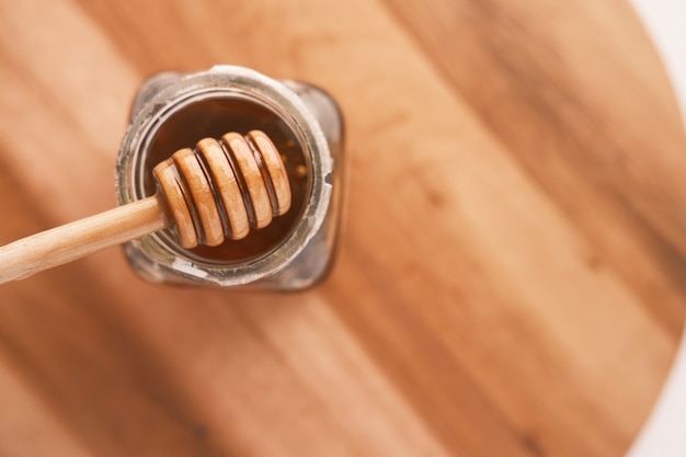 Close up of fresh honey with spoon isolated on wooden table