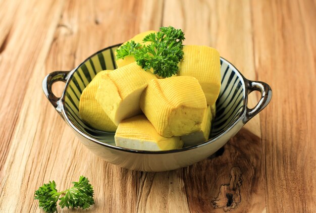 Close Up of Fresh Made Raw Bean Curd Yellow Bandung Tofu Cutting Cube on  Wooden Table (Tahu Susu Lembang). Concept of Vegan Healthy Meal.  Copy Space for Advertisement, Text, or Recipe