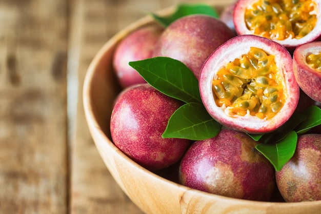 Photo close up fresh passion fruit in wood bowl on wood table in side view with copyspace.