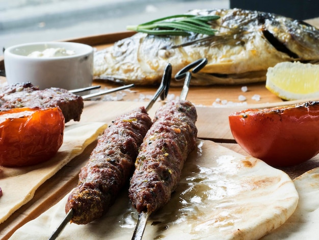 Foto close-up di carne di agnello shish kebab fresca su spiedini e pesce