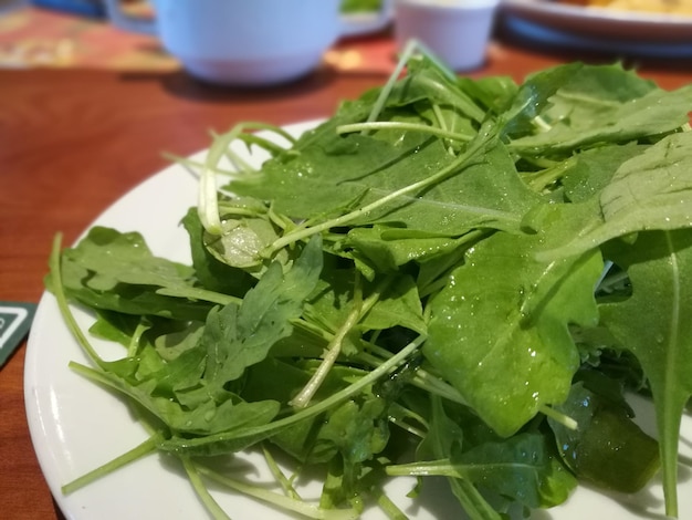 Photo close-up of fresh spinach in plate on table