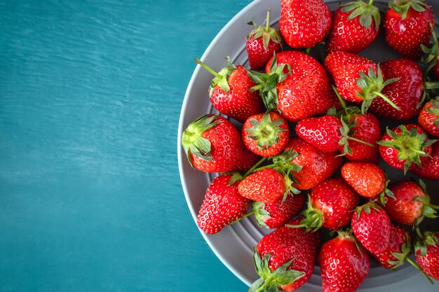 Close up of a fresh strawberry in a bowl on light blue background