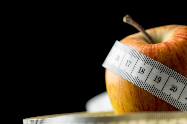 Close-up of a fresh tasty apple wrapped with a white measuring tape