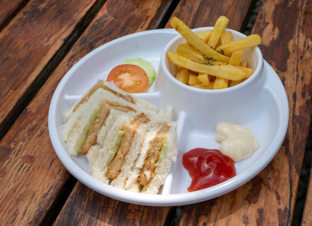 Close up of fresh tasty sliced burger and french fries with white plate on wooden table