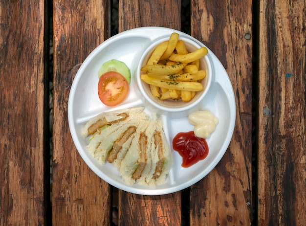 Близкий взгляд на свежий вкусный нарезанный бургер и картошку фри с белой тарелкой на деревянном столе
