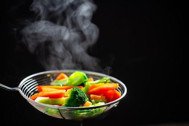 Photo close-up of fresh vegetables in bowl against black background