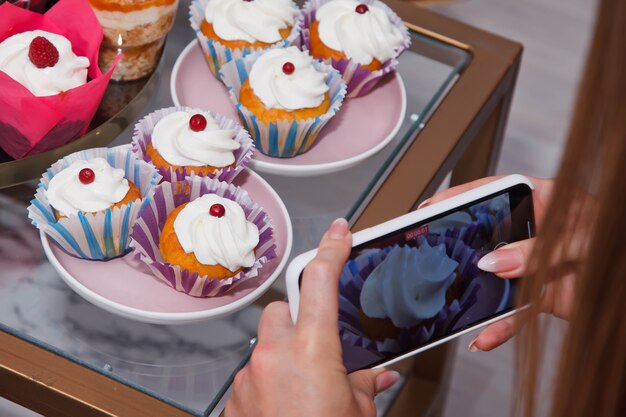 Photo close up of freshly baked cakes and cupcakes in a row at table. healthy summer pastry dessert. berry tartlets or cake with cream cheese top view. copyright space for site