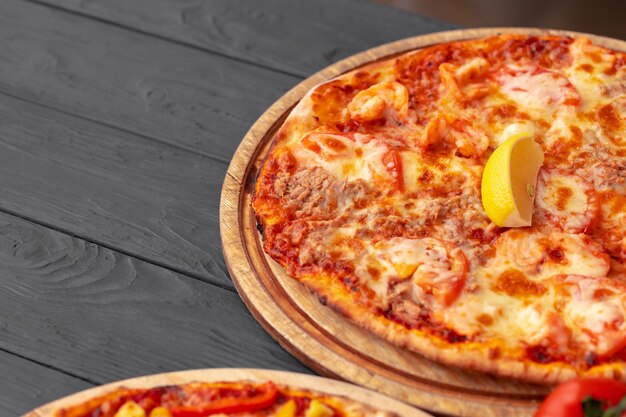 Close up of freshly baked pizza on black wooden table