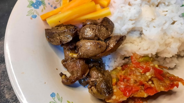 Close up, fried chicken liver with chili sauce and boiled carrots as a side dish