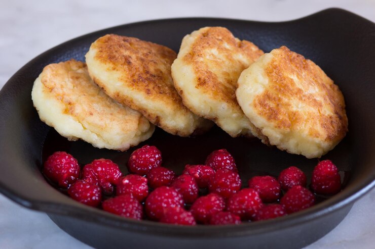 Photo close up fried homemade syrniki with fresh raspberry on black plate on the white background