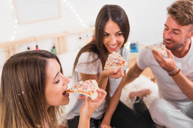 Foto primo piano dell'amico che mangia pizza davanti alle coppie