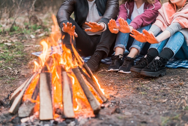 Photo close-up friends warming at fire camp