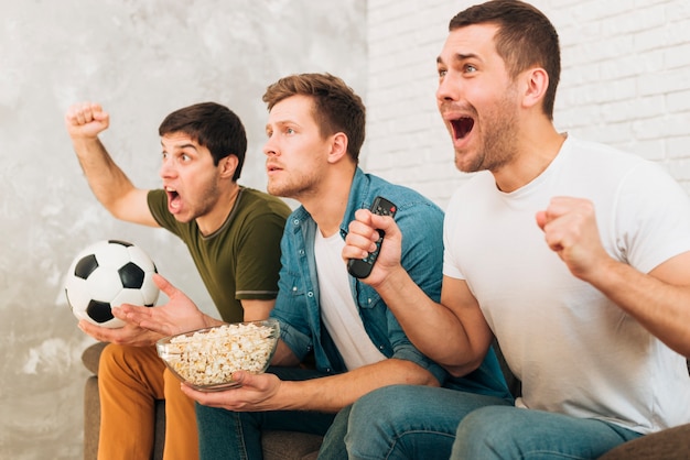 Primo piano degli amici che guardano la partita di football americano che grida e che grida