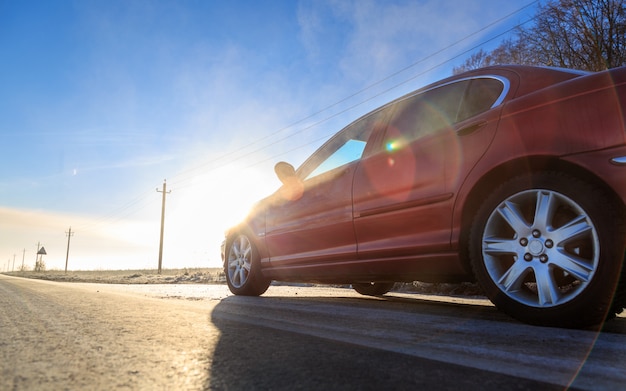 Chiuda sulla parte anteriore di nuova automobile rossa sulla strada asfaltata un giorno soleggiato