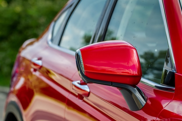 Close up front view of car side mirror. Front rear view mirror on the car window. Car exterior details. Red car mirror.