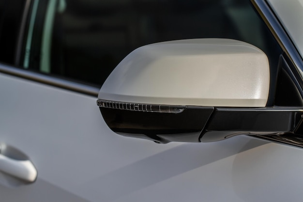 Close up front view of car side mirror. Front rear view mirror on the car window. Car exterior details. White car mirror.