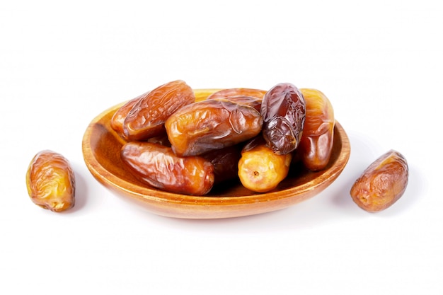 Close up fruits of date palm in wooden bowl on white background