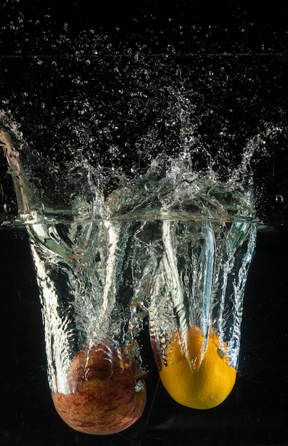 Foto close-up di frutti che schizzano acqua su uno sfondo nero