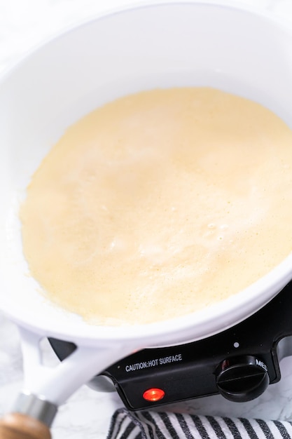 Close up. Frying crepes on a white frying pan.